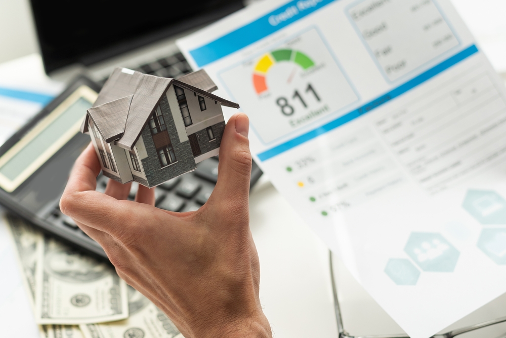 Person reviewing a credit report holding a small cardboard model of a house.