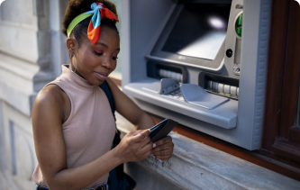 Woman looking at her wallet in front of an ATM machine