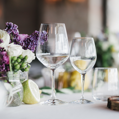 Two empty wine glasses on a table with purple flowers.