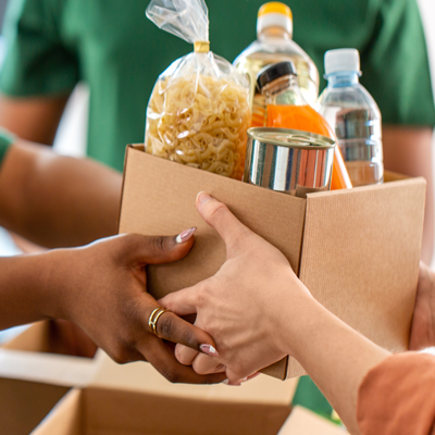 Someone handing a box of packed food items to another person